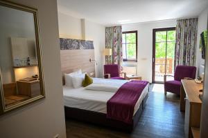 a hotel room with a bed and two purple chairs at Weingut Sandwiese Winzerhotel in Worms +73 photos