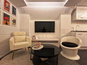 a living room with a tv and a chair and a table at Gite Urbain - Asclepios in Épernay