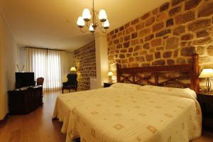 Un dormitorio con una cama grande y una pared de piedra. en La Hosteria de Castroviejo, en Duruelo de la Sierra