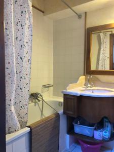 une salle de bain avec un lavabo, une baignoire et un miroir dans l'établissement OLCA Les Houches, aux Houches