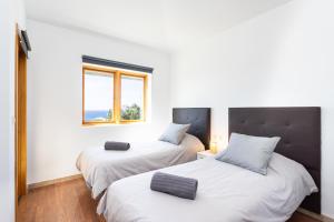 two beds in a room with two windows at Casa Malo Garden and sea view townhouse in La Jaca