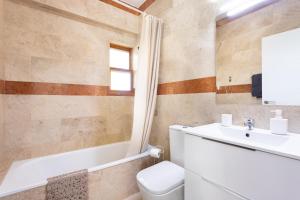 a bathroom with a sink and a toilet and a tub at Casa Malo Garden and sea view townhouse in La Jaca +28 photos