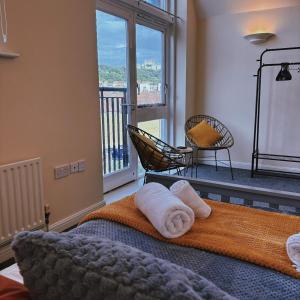a bedroom with a bed with towels and a balcony at The Dover House with river and Castle views in Dover