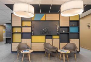 a waiting area with chairs and tables in a lobby at B&B HOTEL Rouen Centre in Rouen