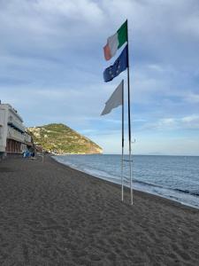 two flags on a beach next to the ocean at Hotel Angelino in Ischia