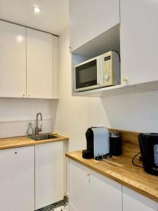 a kitchen with white cabinets and a microwave at Le Cocon - 2 Bedrooms in Grenoble