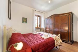 a bedroom with a red bed and a wooden cabinet at Borgo Panicale with Shared Pool and Garden in Panicale