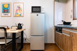 einen weißen Kühlschrank in einer Küche mit einem Tisch in der Unterkunft Animal Art Apartment Type 12 in Tokio