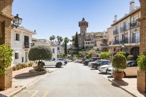 a street with parked cars and a clock tower at Golf Residence Casa Aida in Mijas