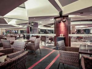 a restaurant with tables and chairs and a bar at Mercure Convention Center Ancol in Jakarta