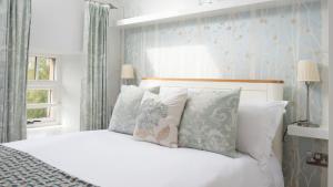 een slaapkamer met een bed met witte lakens en kussens bij Budle Bay Loft in Bamburgh