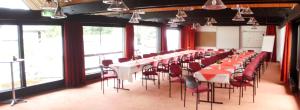 a row of tables and chairs in a room with windows at Landhotel Westerwald in Ehlscheid