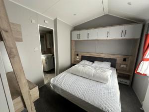 a small bedroom with a bed with white sheets at Royal Oak Caravan Park in Skegness