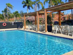a swimming pool with chairs and a pavilion at ibis Styles Taubate in Taubaté