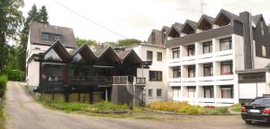 ein großes weißes Gebäude mit einem Dach auf einer Straße in der Unterkunft Landhotel Westerwald in Ehlscheid