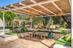un patio extérieur avec des meubles verts et une pergola en bois dans l'établissement Trulli cicale e olive - Le Case di Valentina, à Ceglie Messapica