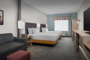 TooeleHome2 Suites By Hilton Tooele的一间带床和椅子的酒店房间