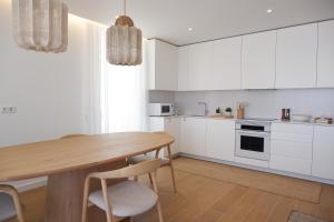 a kitchen with a wooden table and white cabinets at T3 Baía de São Martinho in São Martinho do Porto