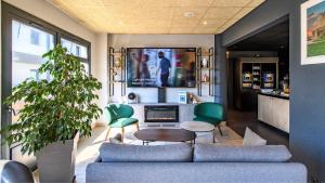 a living room with a blue couch and green chairs at Campanile PRIME - Nîmes Centre in Nîmes