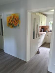 a white kitchen with a painting on the wall at Naturblick in Aukrug