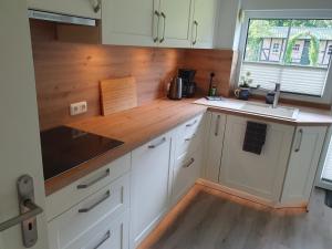 a kitchen with white cabinets and a wooden counter top at Naturblick in Aukrug