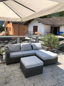 a couch with pillows on a patio under an umbrella at Appartamento Preglia Piemonte 