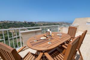 a wooden table and chairs on a balcony with a view at Luxury Apartment Valley Views B11 in Xagħra