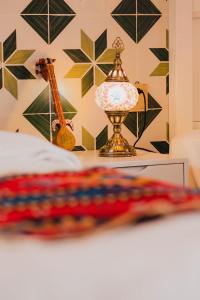 a bed with a lamp and a guitar on a table at 一千零一夜喀什古城民宿 Kashgar Ancient City Scenic Area in Kashgar