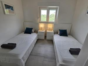 2 camas en una habitación pequeña con 2 lámparas en Apartment Monika Maslenica, en Maslenica