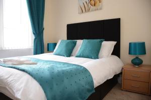 - une chambre avec un grand lit et des oreillers bleus dans l'établissement Townhead Apartments Gallery View, à Paisley