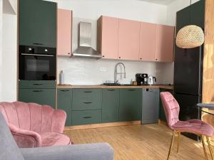 a kitchen with green cabinets and pink chairs at Goździkowy Apartament in Frombork