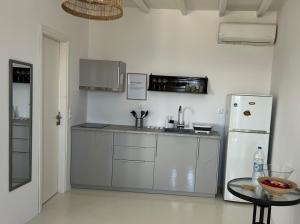 a white kitchen with a refrigerator and a table at La Priva Calma in Agios Ioannis