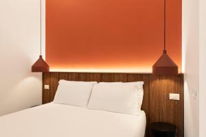 a bedroom with a bed with two lights above it at RELSTAY - Assarotti Suites in Genoa