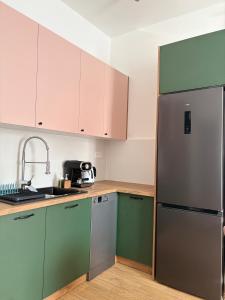 a kitchen with green cabinets and a stainless steel refrigerator at Goździkowy Apartament in Frombork +6 photos