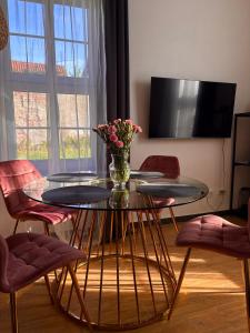 a glass table with a vase of flowers on it at Goździkowy Apartament in Frombork