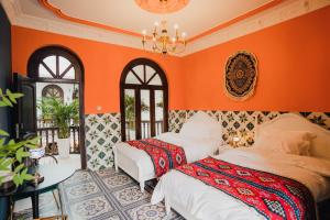 two beds in a room with orange walls at 一千零一夜喀什古城民宿 Kashgar Ancient City Scenic Area in Kashgar