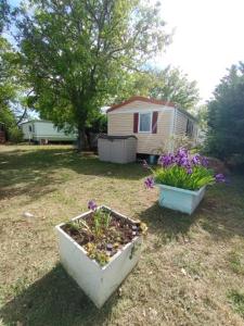 two flower boxes sitting in a yard with a house at MOBILHOME 4 places in Sainte-Croix-de-Verdon