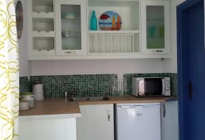 a kitchen with white cabinets and a microwave at Dove View in Andros