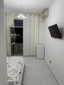a white room with a bed and a flat screen tv at ELIO's Room in Durrës