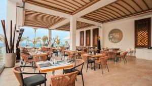 a restaurant with tables and chairs and the ocean at Cavo Maris Beach Hotel in Protaras