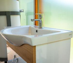 ein weißes Waschbecken in einem Badezimmer mit Spiegel in der Unterkunft Arditi's Cabin in Bogë