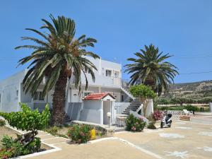 a white building with palm trees in a parking lot at Garden Villa in Karpathos