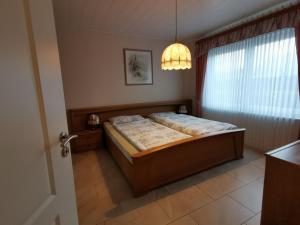 a bedroom with a bed and a window and a chandelier at Ferienhaus Mooi Huus 95157 in Rhauderfehn