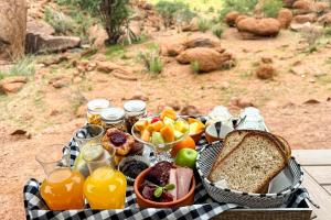 a picnic table with a basket of fruit and bread at Camp Kipwe - Damaraland in Twyfelfontein