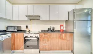 ドバイにあるStunning Sea View 2BR Luxury Apartment in Marinaの白いキャビネットとステンレス製の冷蔵庫を備えたキッチン