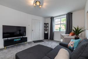a living room with a couch and a flat screen tv at Countryside Stay Near JCB, Peaks & Alton Towers in Rocester