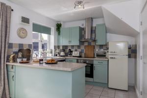 a kitchen with blue cabinets and a white refrigerator at Countryside Stay Near JCB, Peaks & Alton Towers in Rocester