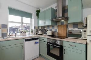 a kitchen with blue cabinets and a stove top oven at Countryside Stay Near JCB, Peaks & Alton Towers in Rocester +24 photos