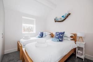 zwei Betten in einem Zimmer mit weißen Wänden in der Unterkunft Charlotte Cottage - Minutes from Poole Park, with Feature Log Burner in Poole