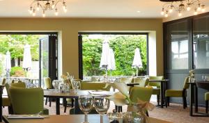 a dining room with tables and chairs and windows at South Lawn Hotel in Lymington